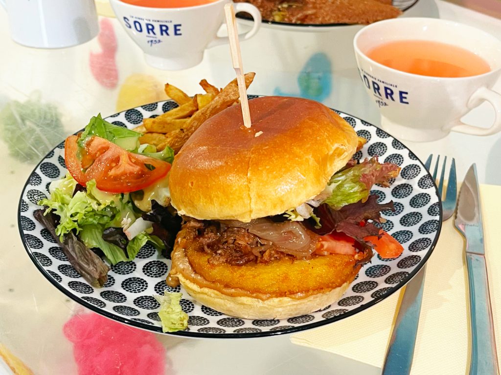 Burger Le Gascon à l'effiloché de canard confit, Galette de pommes de terre, Sauce au Poivre, Salade, Tomate et oignon confits.. Servi avec frites, salade et deux tasses de cidre.