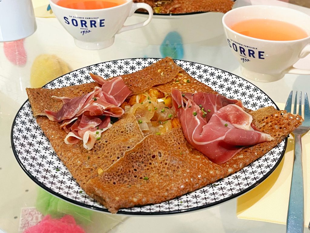 Galette Oncle Pierre avec camembert, pommes de terre sautées, jambon cru et emmental, servie avec deux tasses de cidre.