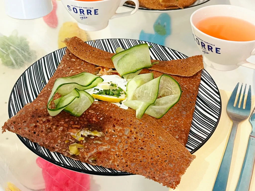 Galette Mamie Bigoude au saumon fumé, fondue de poireaux, crème d’aneth et concombre, accompagnée de deux tasses de cidre.