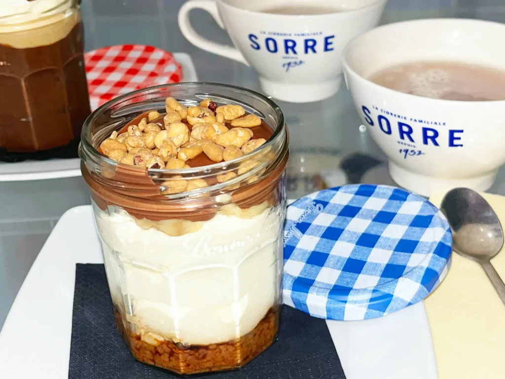Ce pot gourmand Mamie Bigoude, nommé "TATA", est un assemblage parfait de mousse mascarpone façon tiramisu, de Nutella, de banane et de noix de pécan caramélisées, avec des éclats de spéculoos au café.